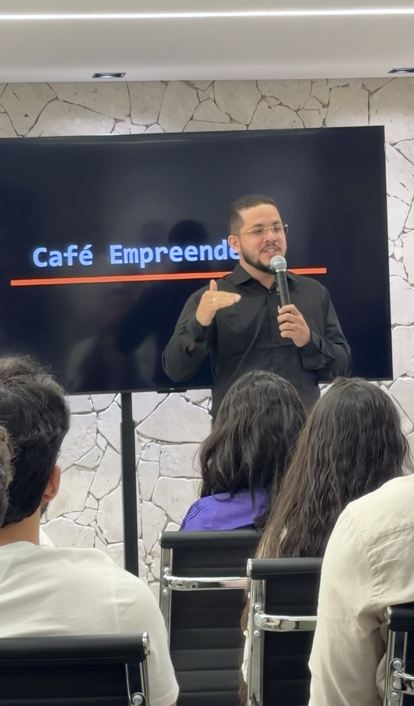 Valdiner Rocha falando ao microfone para participantes de um encontro presencial.